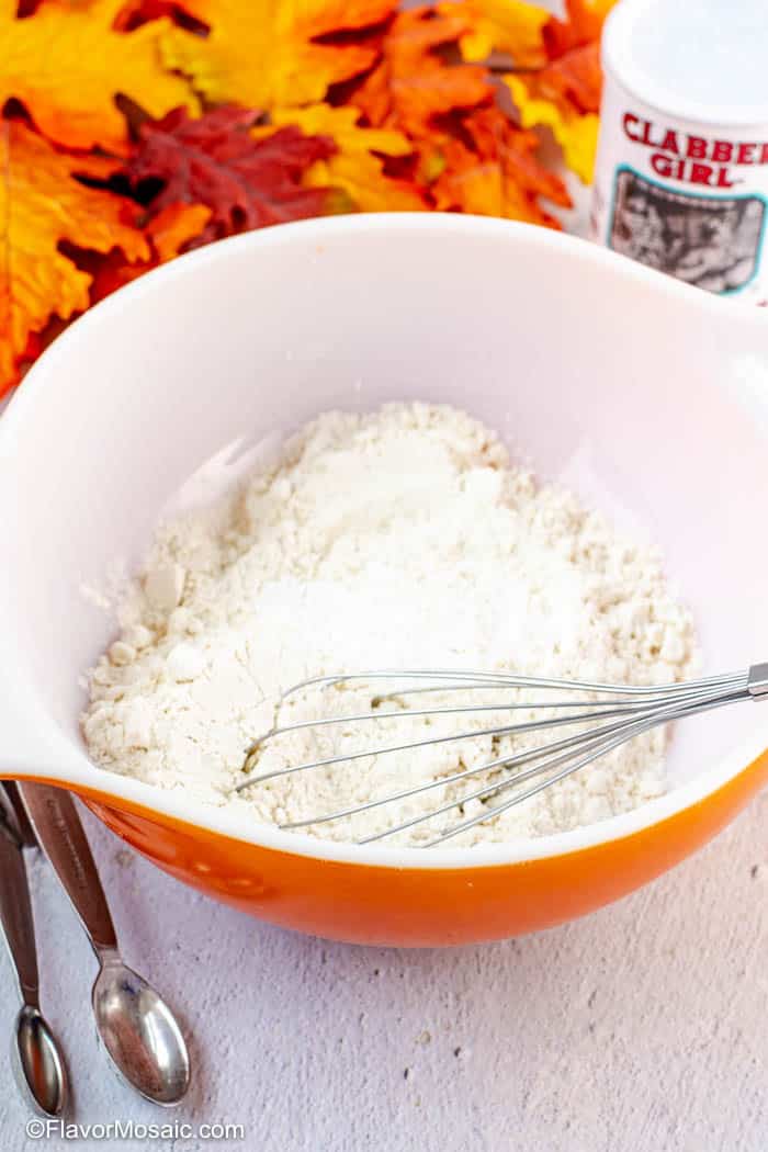All-purpose flour and baking powder in a bowl with a whisk.