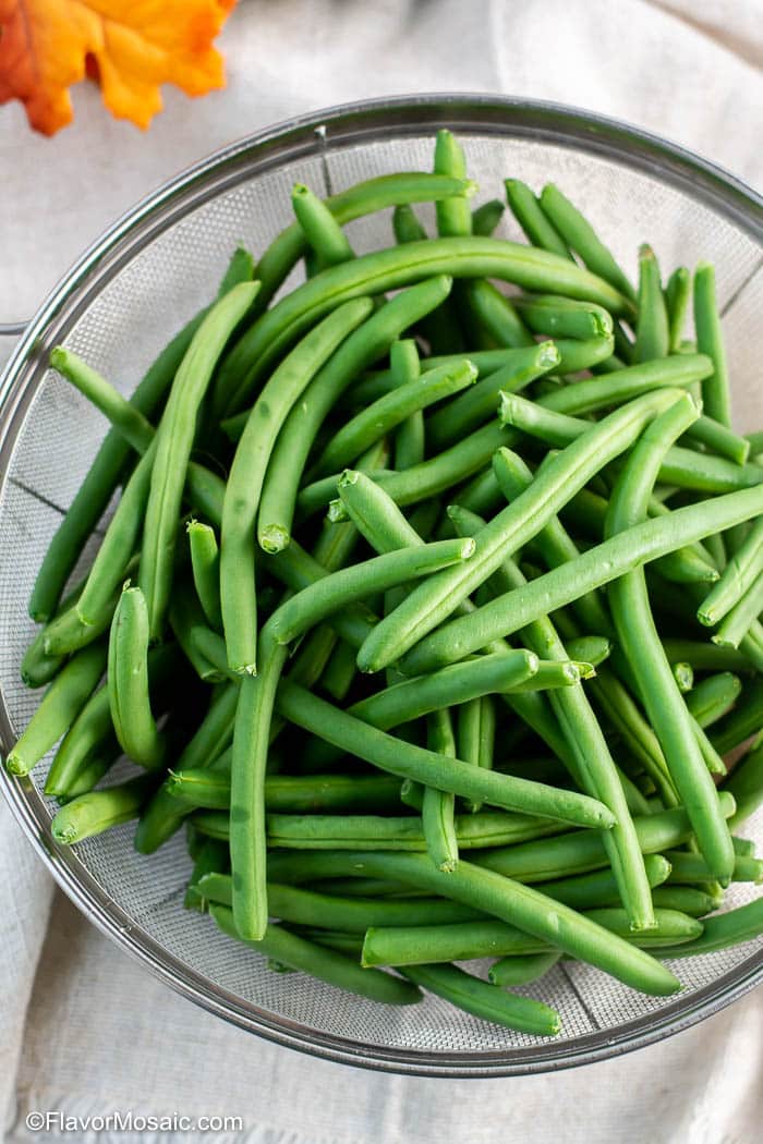 Overhead view of uncooked fresh green beans in a strainer.