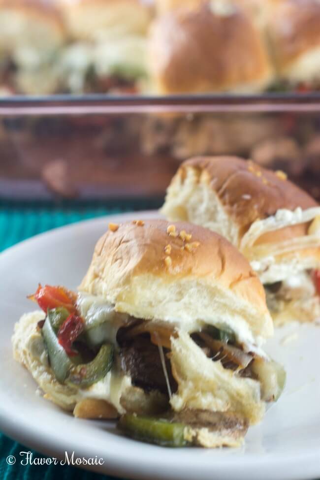 Jalapeno Popper Philly Cheesesteak Sliders on a white plate with the rest in a baking dish in the background.