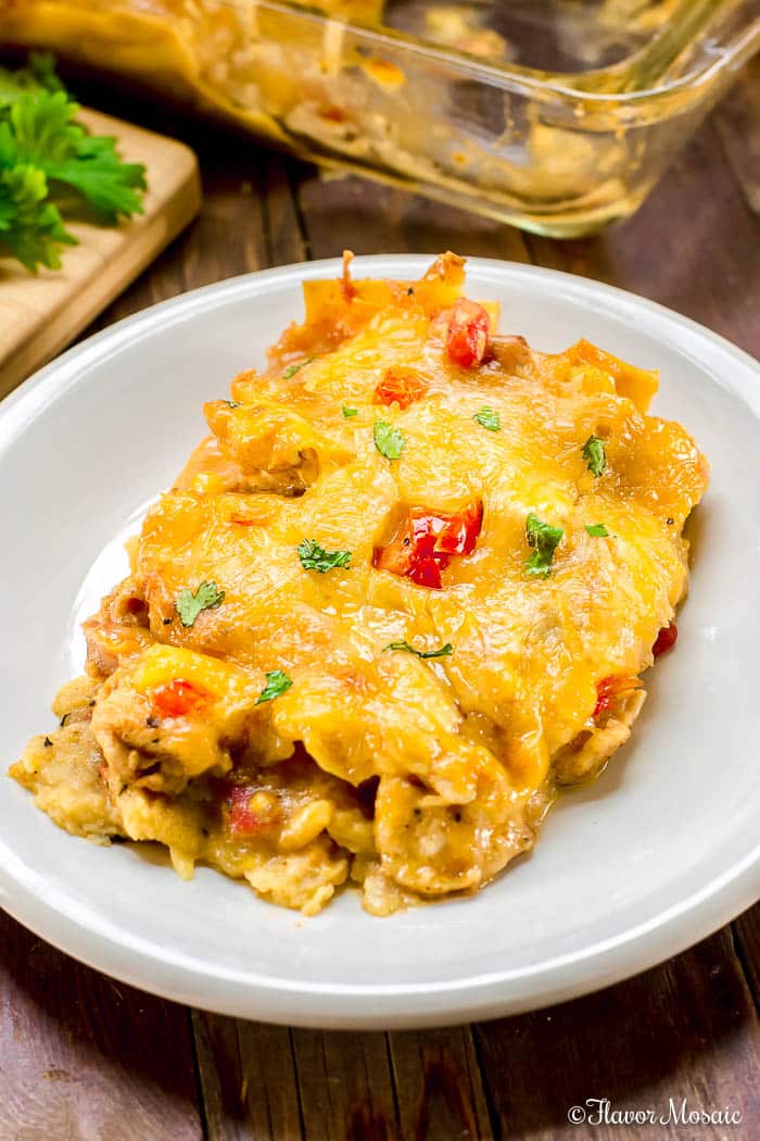 A serving of King Ranch Chicken Casserole on a white plate with a wood background.