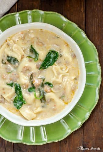 Sausage Tortellini Soup - Instant Pot Version - overhead photo of creamy Sausage Tortellini Soup in white bowl on green plate with dark wood background.