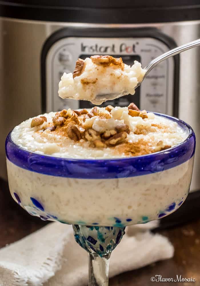 Rice Pudding in a Margarita glass topped with cinnamon and pecans in front of an Instant Pot pressure cooker.
