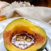 Instant Pot Acorn Squash served on a white plate and filled with melted butter, brown sugar, and cinnamon.