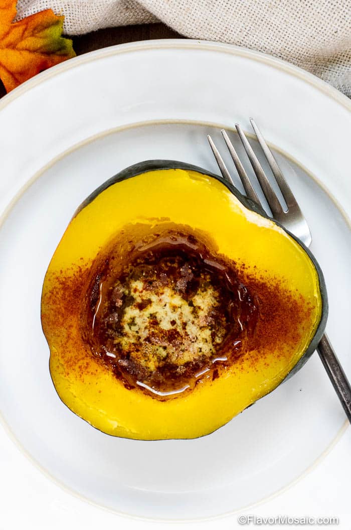 Overhead photo of fully cooked Instant Pot Acorn Squash sitting on a white dinner plate with a fork.
