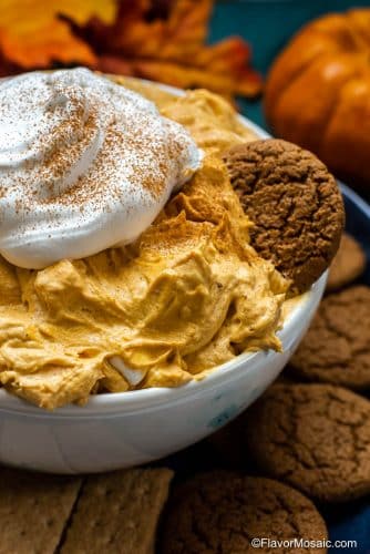 A bowl of Pumpkin Fluff with Cool Whip And Marshmallows and served on a plate with gingerbread snaps.