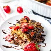 Single serving of Chocolate Strawberry French Toast Casserole sitting on white plate and drizzled in melted chocolate.