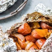 open foil dinner packet with sausage, potatoes, carrots, and onions.