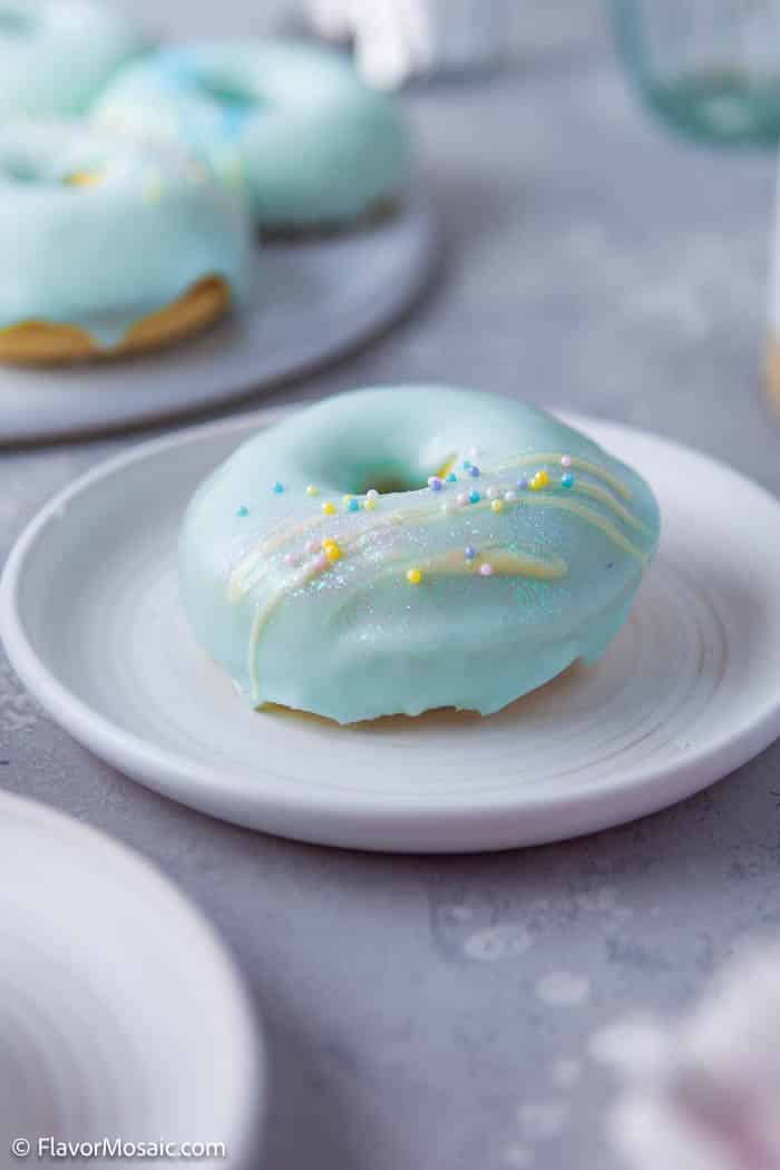 Side view of an individual Vanilla Frosted Donut with teal blue frosting with yellow glitter.