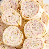 1-Photo Pin with red label and white text showing an overhead close up photo of Ham Salad Tortilla Pinwheels.