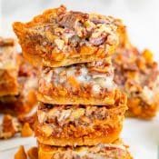 4 Pumpkin Magic Bars stacked on top of each other with more pumpkin bars in the background.