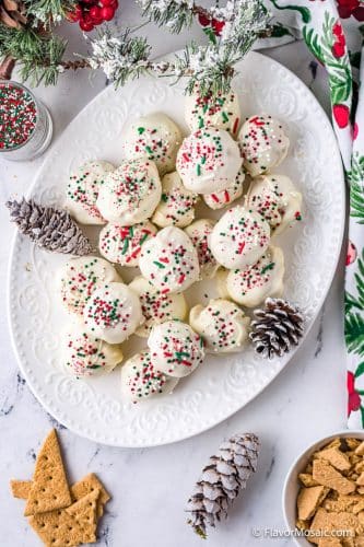 Overhead view of a white platter with Peanut Butter Snowballs topped with red and green sprinkles.