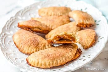 Platter of cajete empanadas with one empanada cut in half to see the caramel filling.