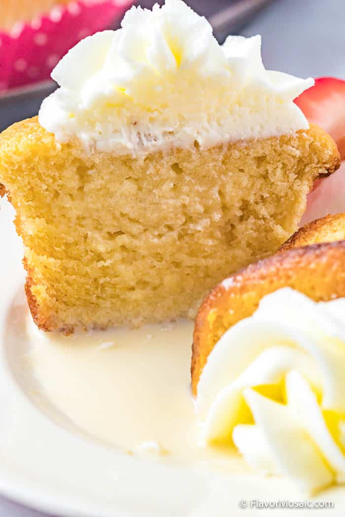 One-half of Tres Leches Cupcakes cut in half vertically sitting on a white plate.