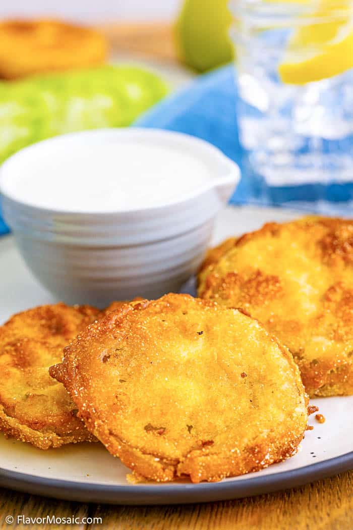 3 sliced Fried Green Tomatoes on a white plate with a small bowl of dipping sauce for fried green tomatoes.