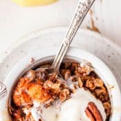 Single ramekin with air fryer apple crisp with whipped cream and pecans