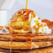 Tall pin with 1 photo of maple syrup being poured over a stack of gingerbread pancakes topped with whipped cream. You can save this pin to Pinterest, so that when you click on it in Pinterest, it takes you to the recipe post on Flavor Mosaic.