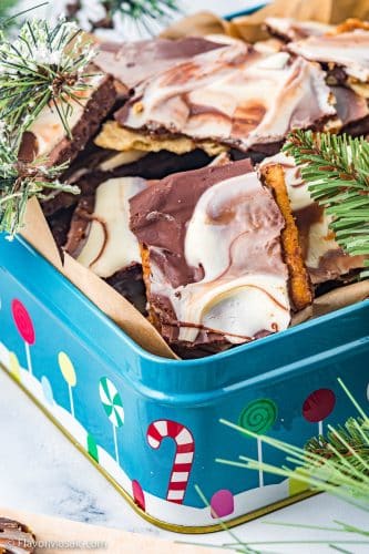 Pieces of Saltine Cracker Toffee inside a blue Christmas tin.