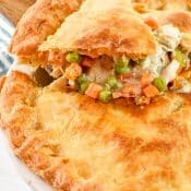 Single serving being lifted out of the chicken pot pie casserole. You can see the flaky crust and the chicken and vegetables in a creamy sauce.